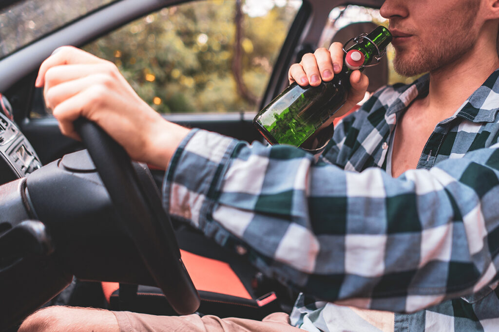 Hombre tomando alcohol al conducir